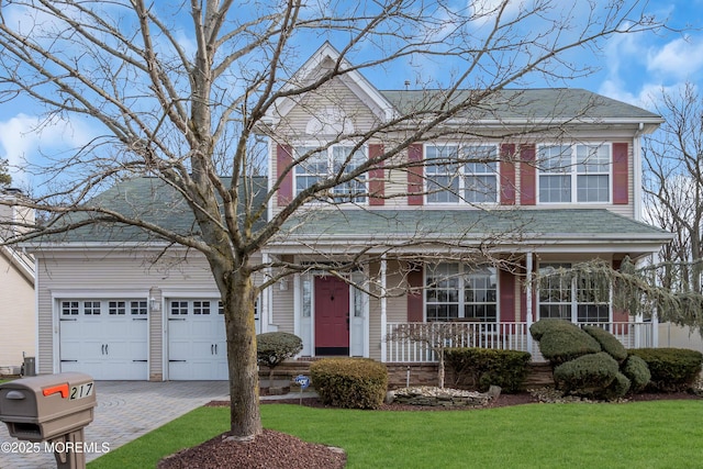 view of front of property with covered porch, a front lawn, decorative driveway, and a garage