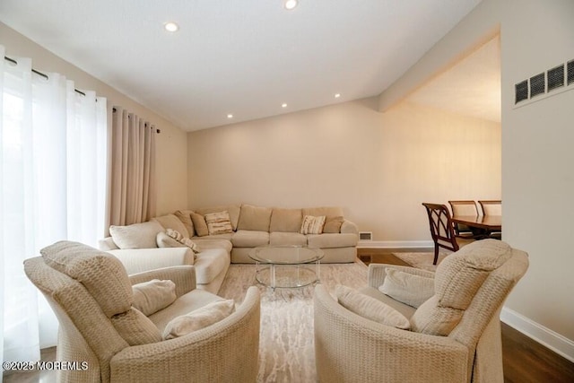 living room featuring baseboards, visible vents, wood finished floors, and recessed lighting