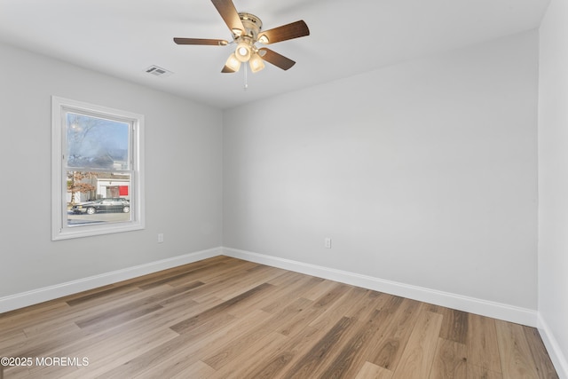 spare room featuring baseboards, visible vents, ceiling fan, and light wood finished floors