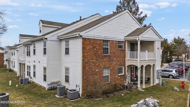 view of side of property featuring a yard, a balcony, and central air condition unit