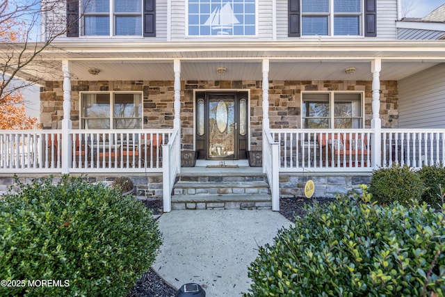 doorway to property featuring stone siding and a porch