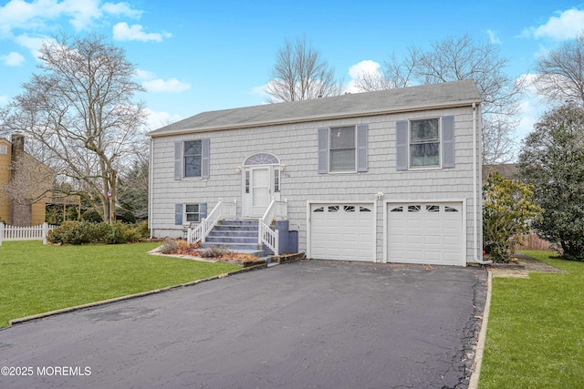 bi-level home featuring an attached garage, aphalt driveway, fence, and a front lawn