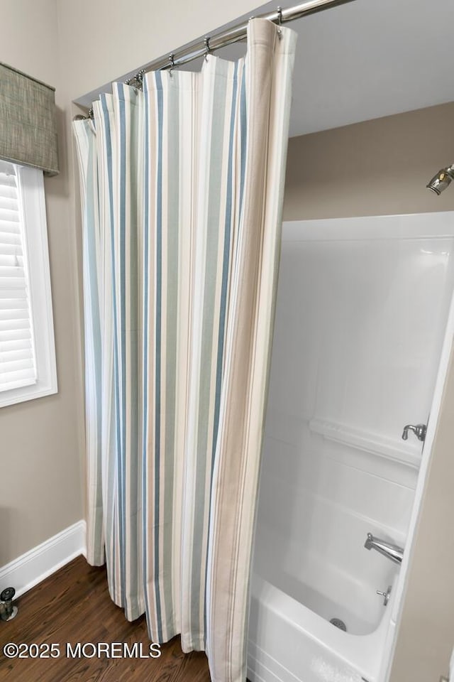 full bath with shower / tub combo, baseboards, and wood finished floors