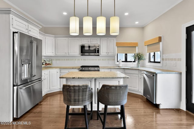 kitchen with a center island, dark wood finished floors, stainless steel appliances, decorative backsplash, and ornamental molding