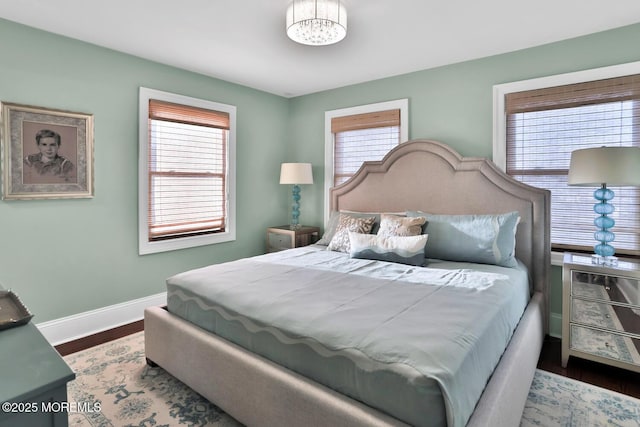 bedroom featuring an inviting chandelier, wood finished floors, and baseboards