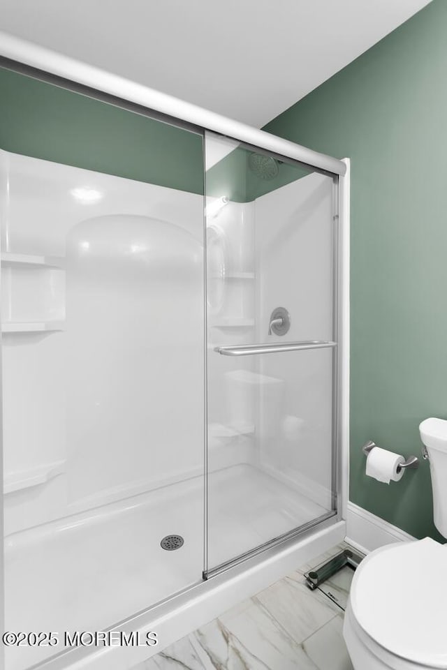 full bath with a stall shower, marble finish floor, and toilet