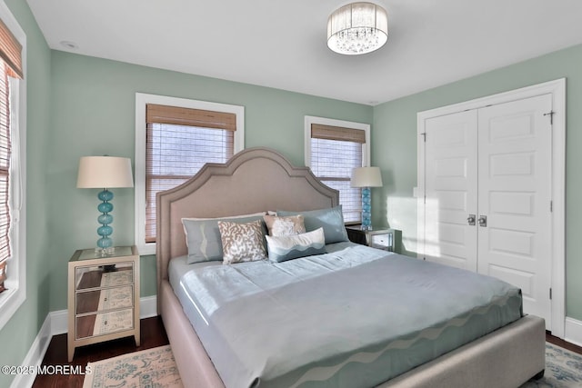 bedroom featuring a chandelier, a closet, wood finished floors, and baseboards