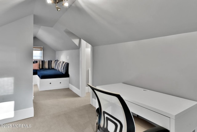 office area featuring light carpet, vaulted ceiling, built in study area, and baseboards