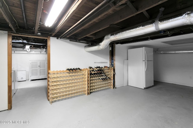 unfinished basement with freestanding refrigerator