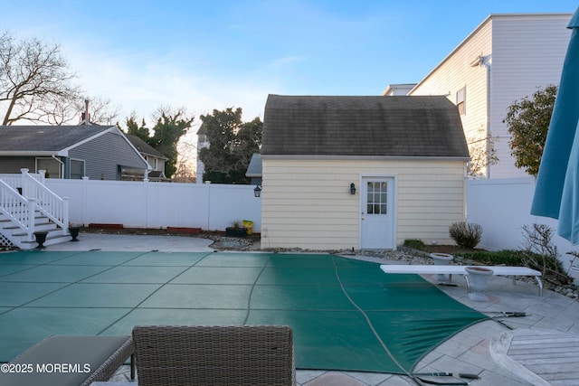 view of swimming pool featuring a patio, an outdoor structure, and a fenced backyard