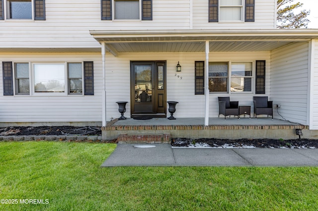 view of exterior entry with covered porch and a lawn