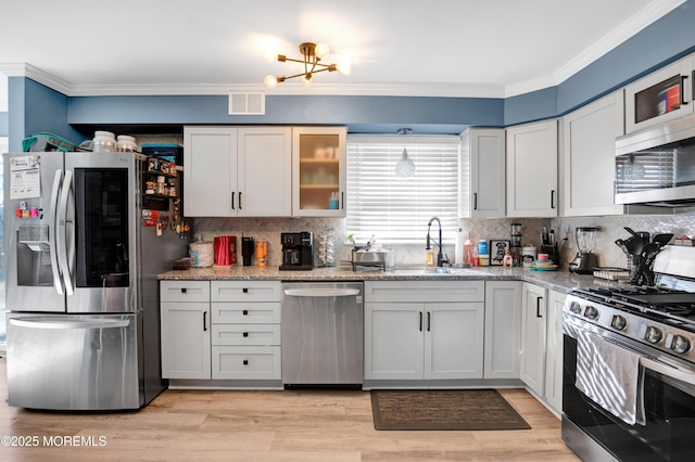 kitchen with light stone counters, stainless steel appliances, a sink, visible vents, and white cabinets