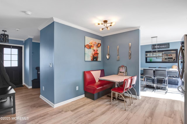 dining space with light wood-type flooring, crown molding, and baseboards