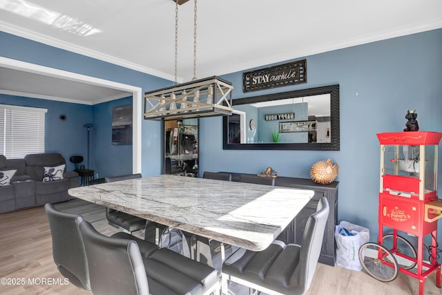 dining room with light wood finished floors and ornamental molding