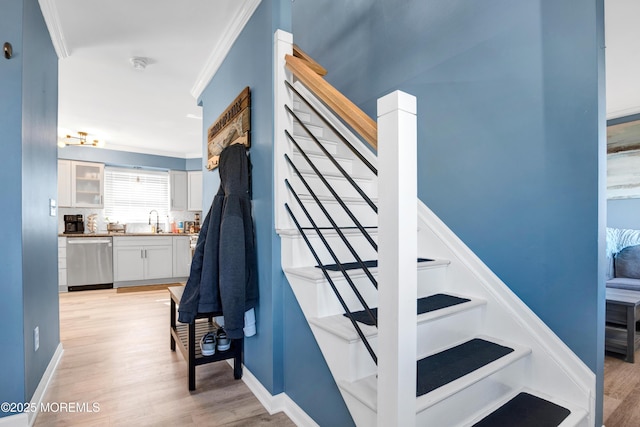 stairs with baseboards, crown molding, and wood finished floors