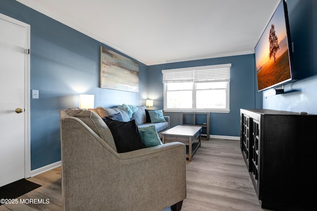 living area featuring ornamental molding, baseboards, and wood finished floors