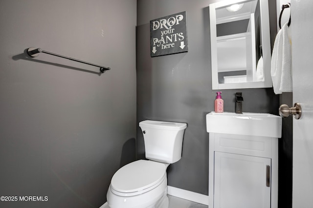 half bathroom with baseboards, vanity, and toilet