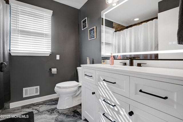 bathroom with toilet, vanity, visible vents, baseboards, and marble finish floor