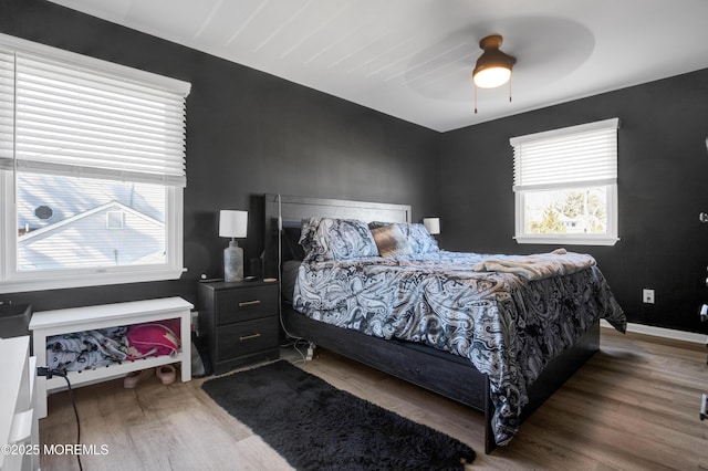 bedroom with ceiling fan, wood finished floors, and baseboards