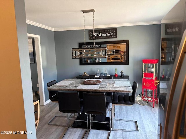 dining area featuring ornamental molding, wood finished floors, and baseboards