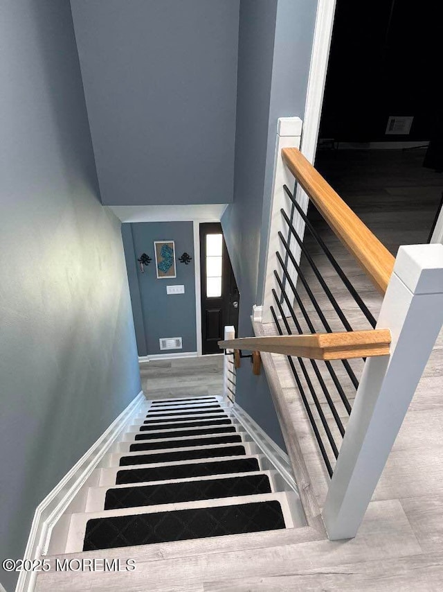 staircase featuring wood finished floors and baseboards