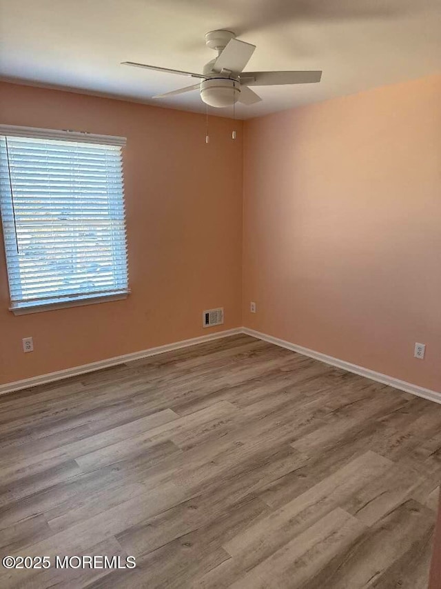 empty room featuring light wood-style floors, visible vents, ceiling fan, and baseboards