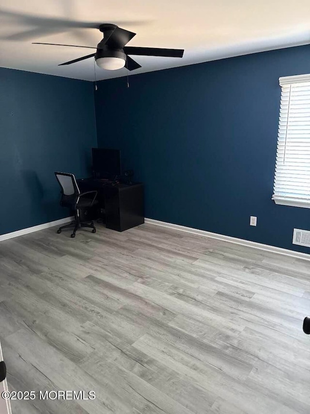 unfurnished office featuring light wood-style floors, visible vents, baseboards, and a ceiling fan