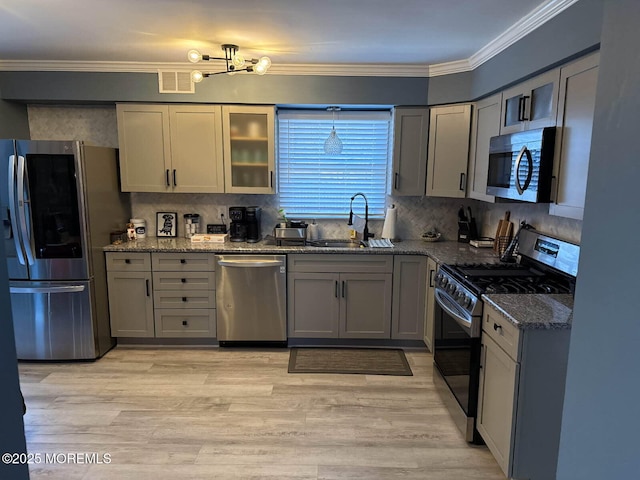 kitchen with stainless steel appliances, visible vents, ornamental molding, a sink, and dark stone countertops