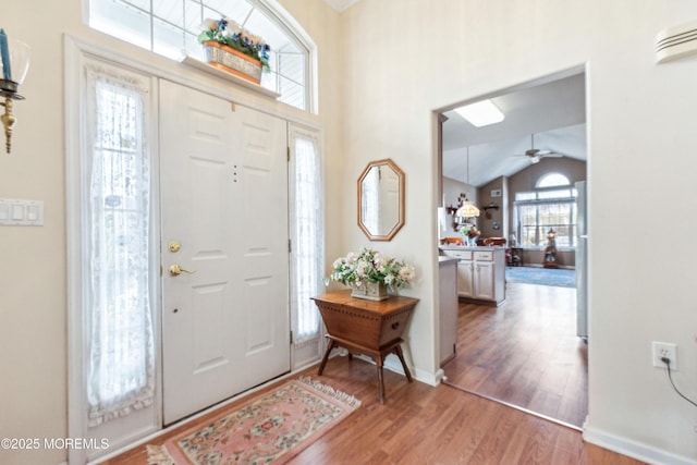 entryway featuring a ceiling fan, baseboards, vaulted ceiling, and wood finished floors