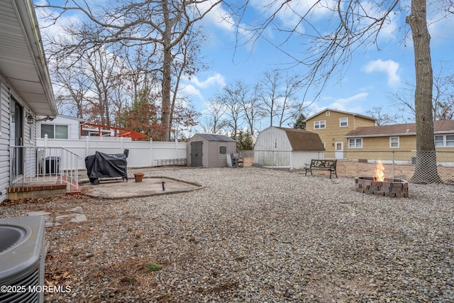 view of yard with an outbuilding, an outdoor fire pit, a fenced backyard, central air condition unit, and a storage unit