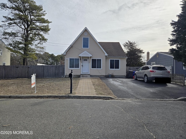 bungalow featuring aphalt driveway, roof with shingles, and fence