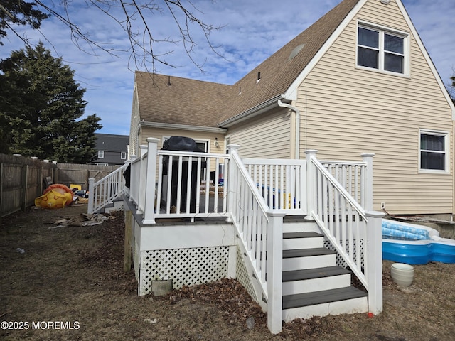 back of house with a deck, a shingled roof, stairway, and fence