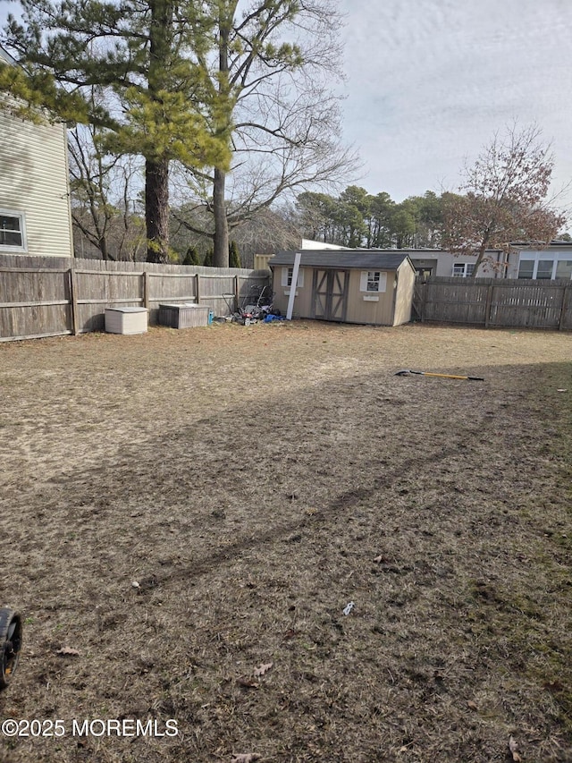 view of yard featuring an outbuilding, a fenced backyard, and a shed