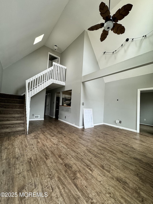 unfurnished living room with high vaulted ceiling, baseboards, stairway, and wood finished floors