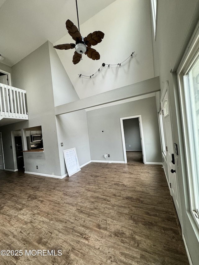 unfurnished living room featuring a ceiling fan, baseboards, high vaulted ceiling, and wood finished floors