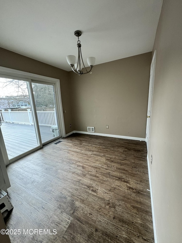 spare room featuring a chandelier, visible vents, baseboards, and wood finished floors