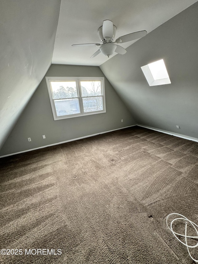 additional living space with ceiling fan, lofted ceiling with skylight, carpet flooring, and baseboards