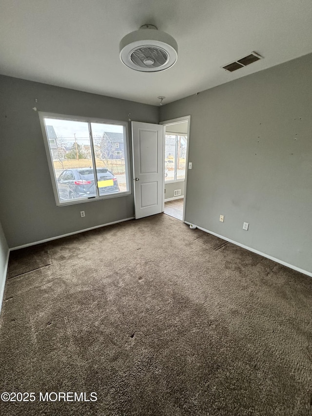 unfurnished room with carpet floors, visible vents, and baseboards