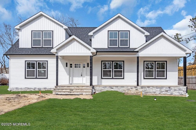 view of front of home with a shingled roof, a front lawn, and a porch