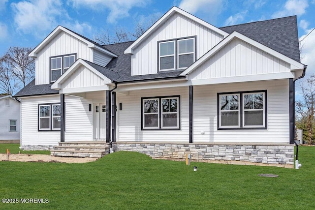 modern farmhouse featuring board and batten siding, a front yard, covered porch, and roof with shingles