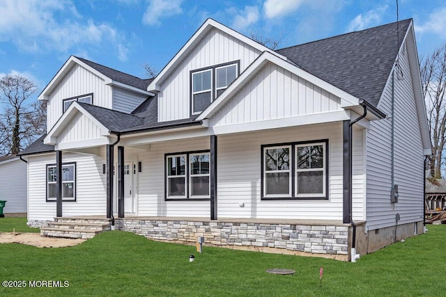 modern farmhouse style home with roof with shingles, a porch, board and batten siding, and a front yard