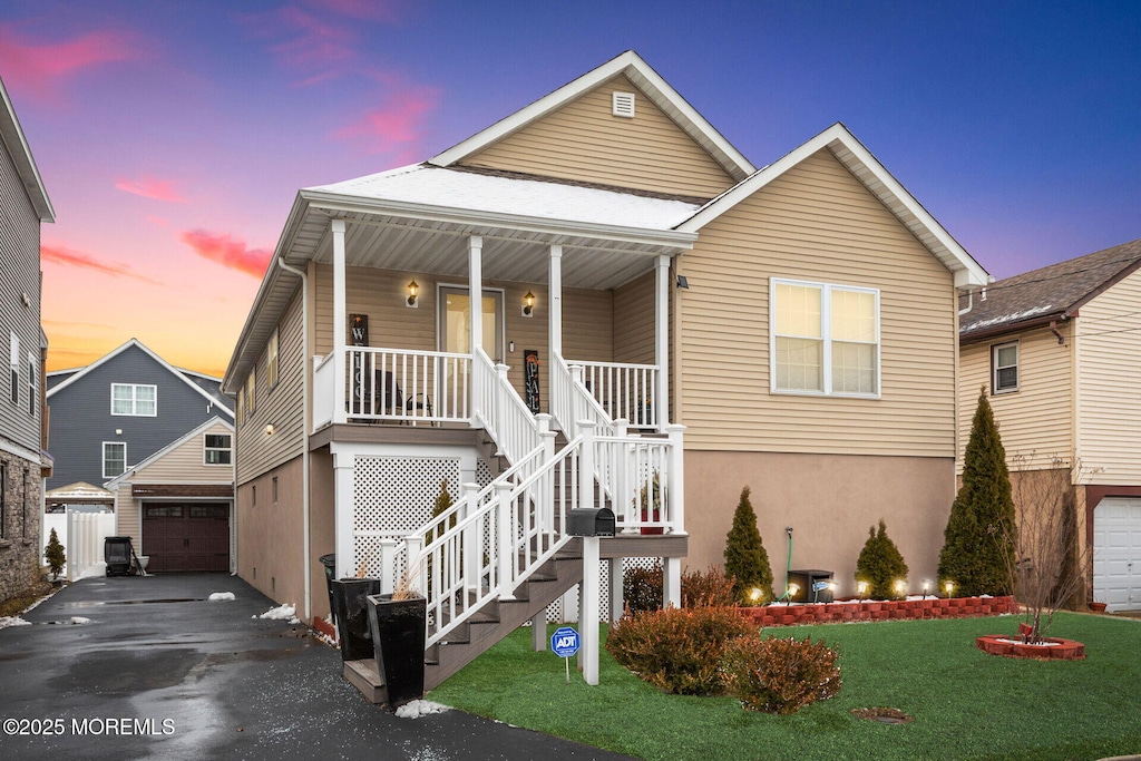 view of front of home with an outbuilding, driveway, a porch, stairs, and a garage
