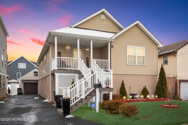 view of front of home with an outbuilding, driveway, a porch, stairs, and a garage
