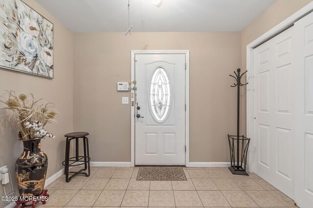 foyer entrance with light tile patterned floors and baseboards