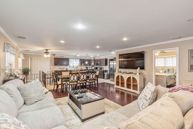living room with light wood-type flooring, visible vents, ornamental molding, plenty of natural light, and ceiling fan