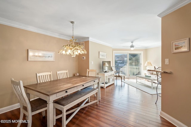 dining area featuring ceiling fan with notable chandelier, ornamental molding, wood finished floors, and baseboards