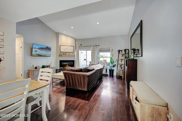 living area with dark wood-type flooring, recessed lighting, and a lit fireplace