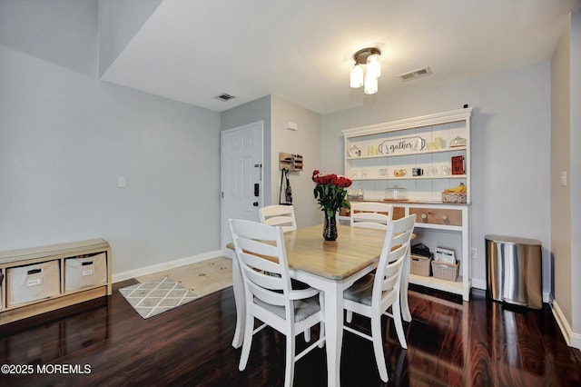 dining room with dark wood-style flooring, visible vents, and baseboards