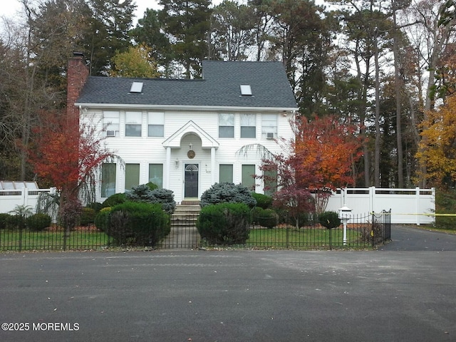 view of front of home featuring a fenced front yard, roof with shingles, and a chimney