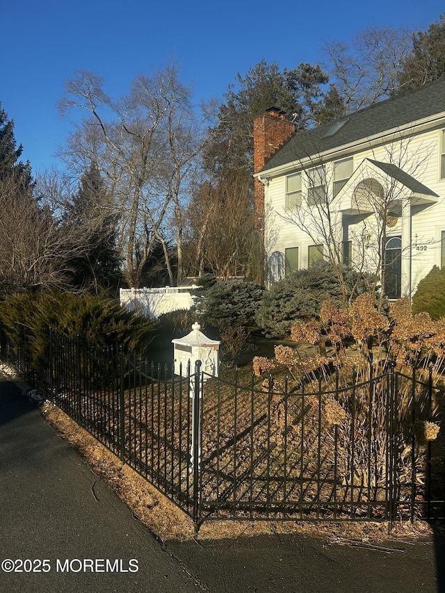 view of property exterior with a fenced front yard and a chimney